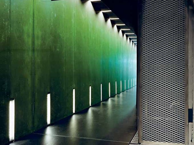 A long green-lit entrance tunnel with repeating light strips at Gamer’s Paradise.
